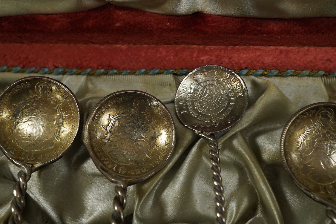 A cased set of twelve assorted white metal coffee spoons, with spiral stems and coin bowls.
